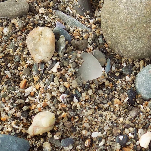 Sea glass grayish piece on beach