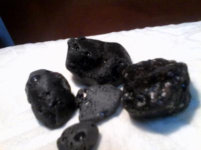 Black shiny pebbles are maybe black glass. They have iron inclusion and can be pulled by a magnet.